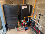 Pump room with 2 x 1200 litre fire water tanks, pipes, and electrical components against a brick wall.