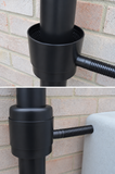Black outdoor drain pipe system attached to a brick wall.
