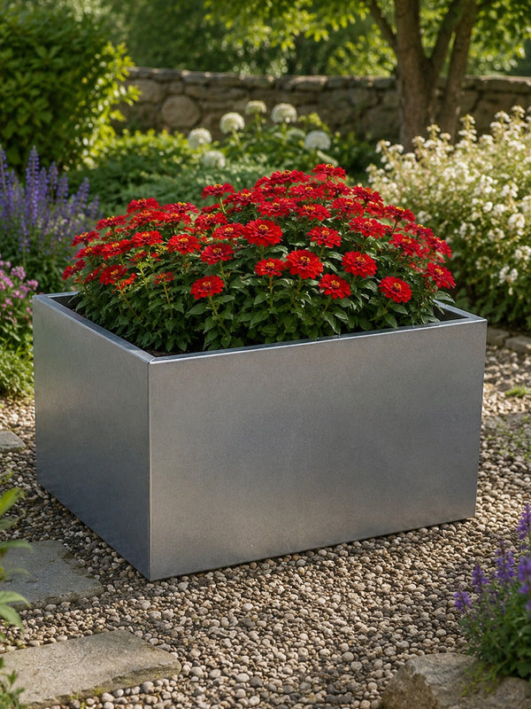 Square metal planter with red flowers in a garden setting